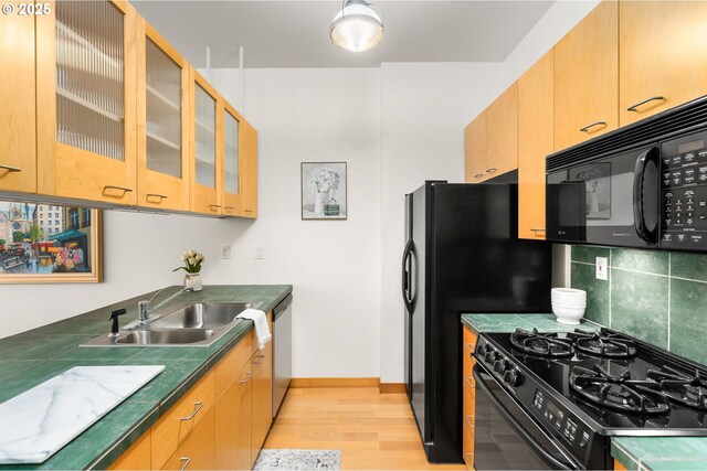 kitchen with sink, backsplash, black appliances, and light wood-type flooring