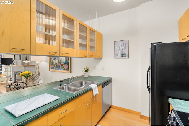 kitchen with stainless steel dishwasher, sink, electric range, light hardwood / wood-style flooring, and black fridge