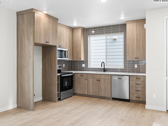 kitchen featuring decorative backsplash, sink, stainless steel appliances, and light wood-type flooring