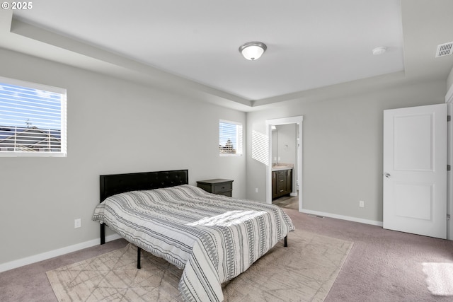 bedroom featuring a raised ceiling and light carpet