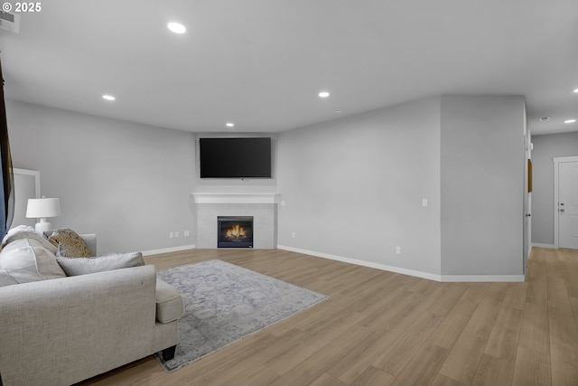 living room with a fireplace and light wood-type flooring