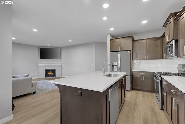 kitchen featuring sink, light hardwood / wood-style flooring, stainless steel appliances, and a center island with sink