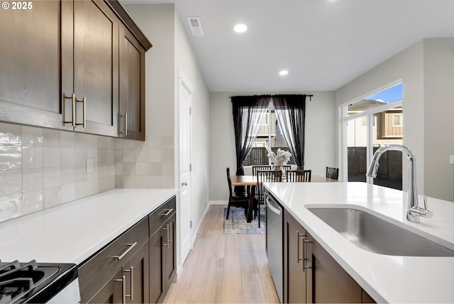 kitchen with dark brown cabinetry, sink, tasteful backsplash, light wood-type flooring, and dishwasher