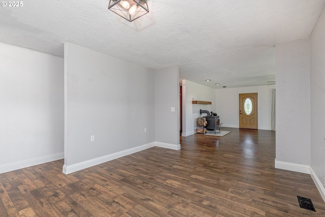 35538 SE Snuffin Rd, Estacada, OR 97023 - unfurnished living room featuring wood finished floors, a wood stove, a textured ceiling, and baseboards