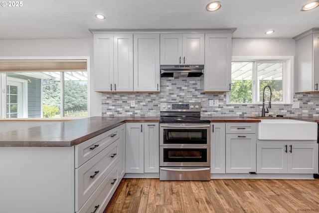 35538 SE Snuffin Rd, Estacada, OR 97023 - kitchen featuring double oven range, range hood, a peninsula, decorative backsplash, and a sink