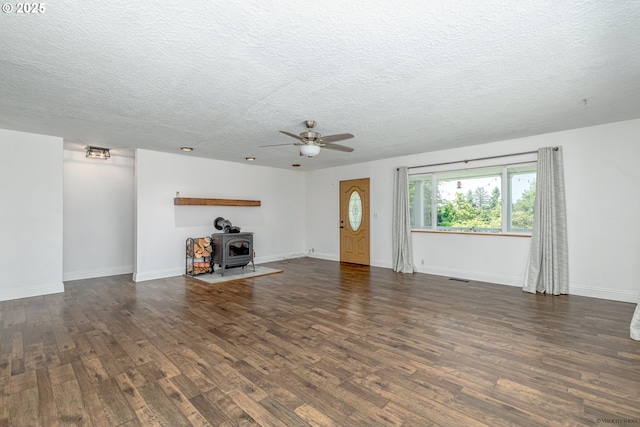 35538 SE Snuffin Rd, Estacada, OR 97023 - unfurnished living room featuring a wood stove, wood finished floors, a textured ceiling, ceiling fan, and baseboards