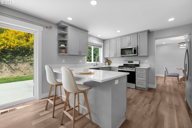 35681 Bella Ridge Loop, Astoria, OR 97103 - kitchen featuring appliances with stainless steel finishes, gray cabinetry, open shelves, light countertops, and a peninsula