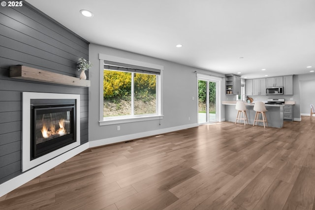 35681 Bella Ridge Loop, Astoria, OR 97103 - unfurnished living room featuring wood finished floors, recessed lighting, a large fireplace, and baseboards