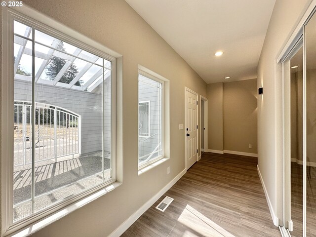 corridor with a healthy amount of sunlight, visible vents, and baseboards