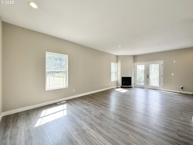 unfurnished living room with french doors, baseboards, visible vents, and wood finished floors