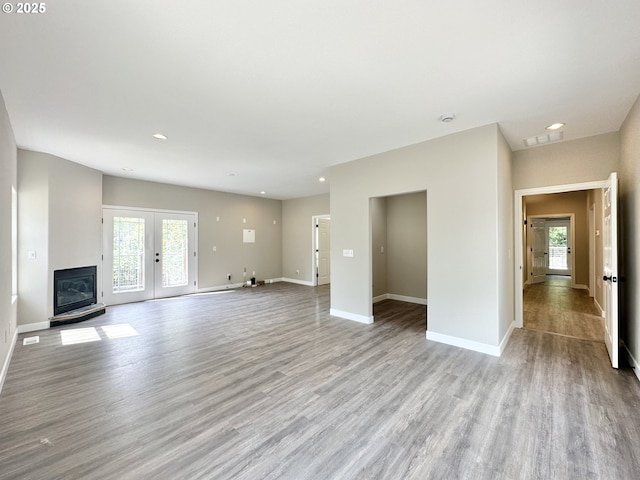 unfurnished living room with french doors, plenty of natural light, and light wood-style floors