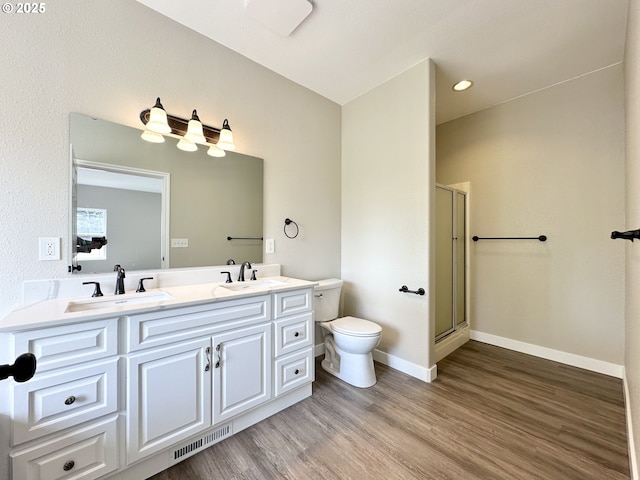 full bathroom with toilet, a stall shower, wood finished floors, and a sink