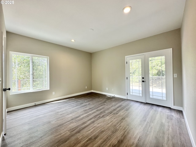 unfurnished room with plenty of natural light, dark wood-type flooring, and baseboards