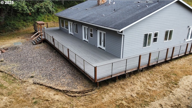 back of house with roof with shingles and a wooden deck