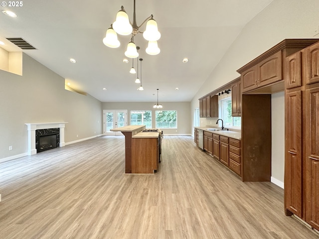 kitchen featuring visible vents, light wood finished floors, a sink, light countertops, and open floor plan