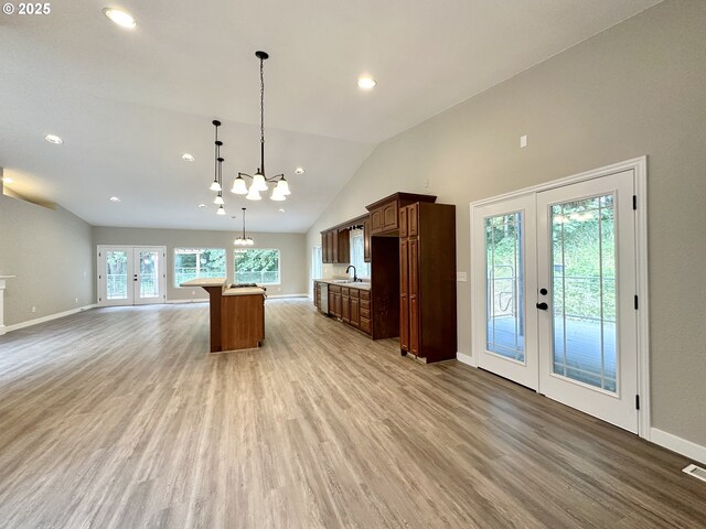 kitchen with open floor plan, light countertops, french doors, light wood-style floors, and a sink