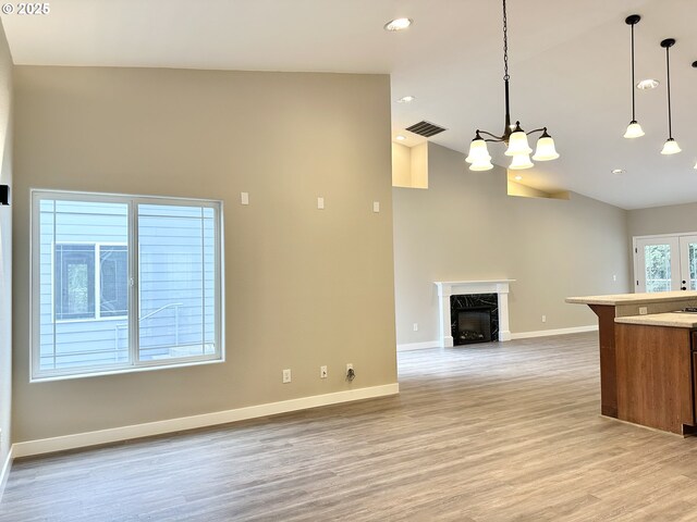 kitchen featuring baseboards, visible vents, light wood-style flooring, decorative light fixtures, and brown cabinets