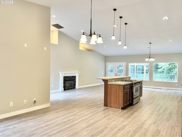 kitchen featuring stainless steel stove, visible vents, open floor plan, and light wood-type flooring