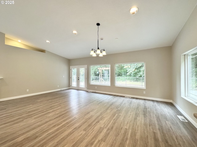 unfurnished room featuring vaulted ceiling, wood finished floors, baseboards, and a chandelier