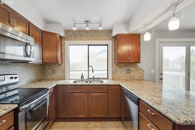 kitchen featuring appliances with stainless steel finishes, tasteful backsplash, sink, hanging light fixtures, and kitchen peninsula