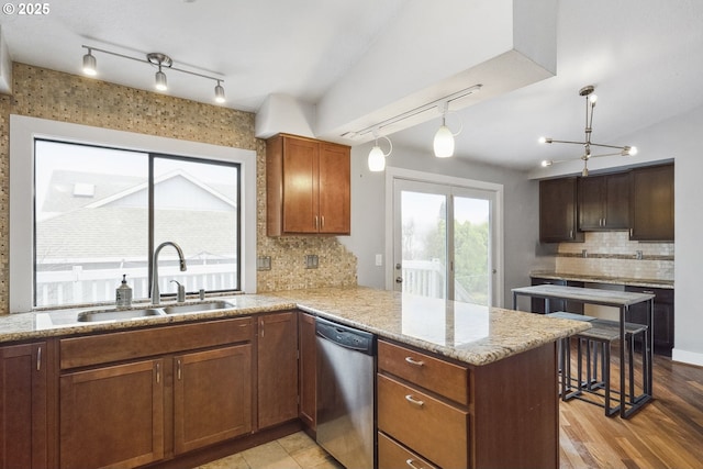 kitchen featuring decorative light fixtures, sink, decorative backsplash, stainless steel dishwasher, and kitchen peninsula