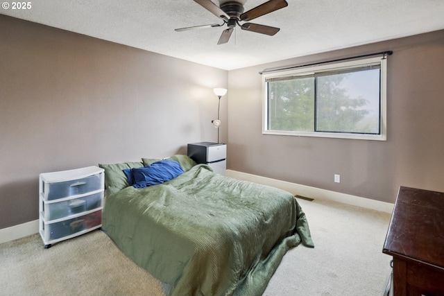 bedroom featuring ceiling fan, light colored carpet, and a textured ceiling