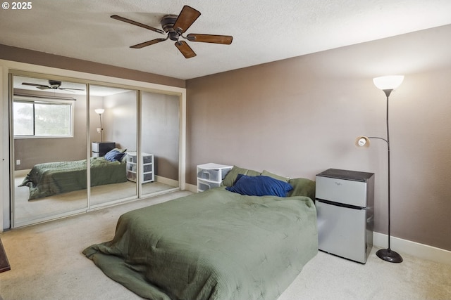 carpeted bedroom with a textured ceiling, stainless steel fridge, a closet, and ceiling fan