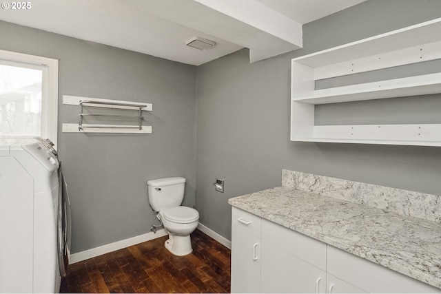 bathroom with hardwood / wood-style flooring, vanity, toilet, and washer and dryer