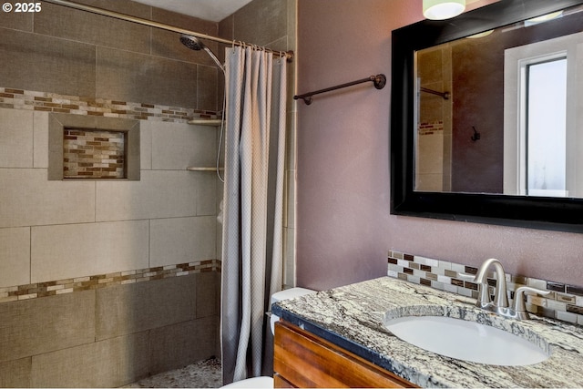 bathroom featuring vanity, curtained shower, backsplash, and toilet