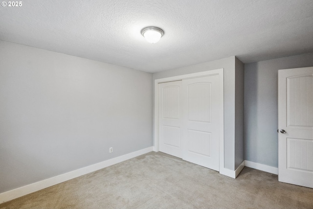 unfurnished bedroom featuring light carpet, a textured ceiling, and a closet