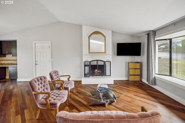 living room with a brick fireplace, hardwood / wood-style floors, and lofted ceiling