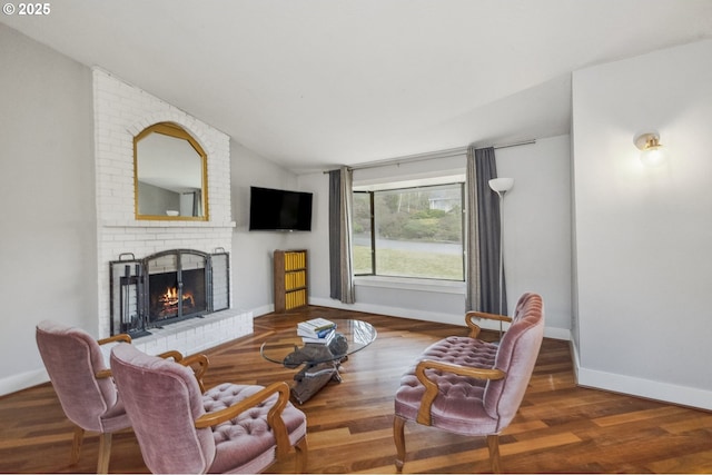 living room with wood-type flooring, a brick fireplace, and lofted ceiling