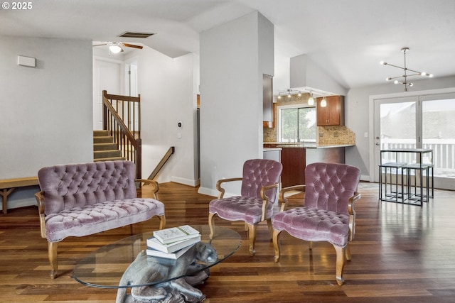 living area with ceiling fan with notable chandelier, dark hardwood / wood-style floors, and vaulted ceiling