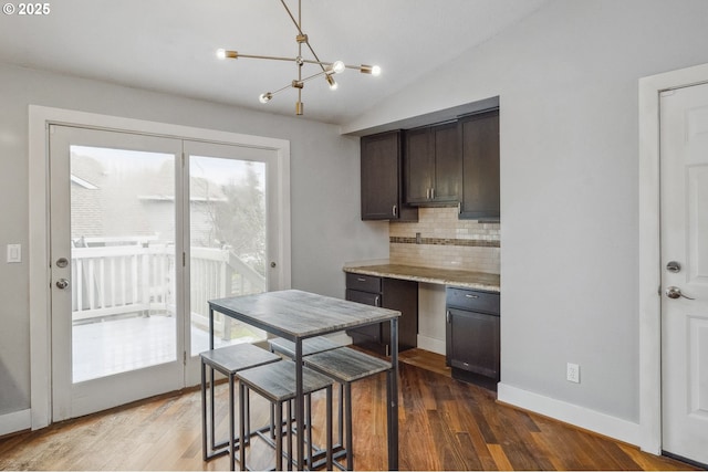 kitchen featuring vaulted ceiling, backsplash, hanging light fixtures, dark wood-type flooring, and dark brown cabinets