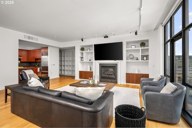 1025 NW Couch St Unit 1320, Portland, OR 97209 - living area featuring a glass covered fireplace, light wood finished floors, rail lighting, and built in features