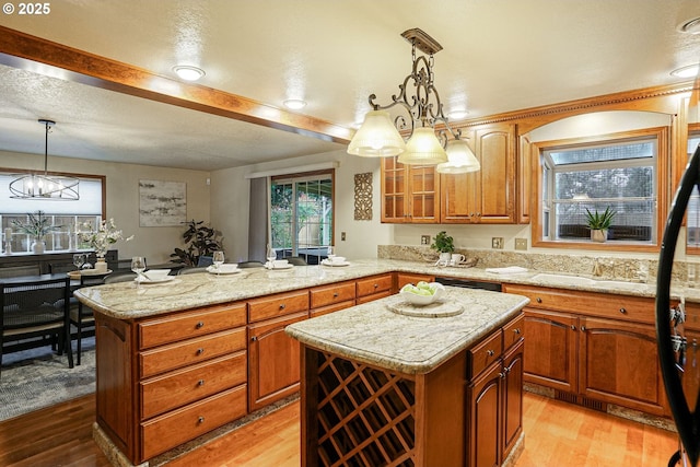 kitchen featuring hanging light fixtures, a center island, a textured ceiling, and light hardwood / wood-style flooring