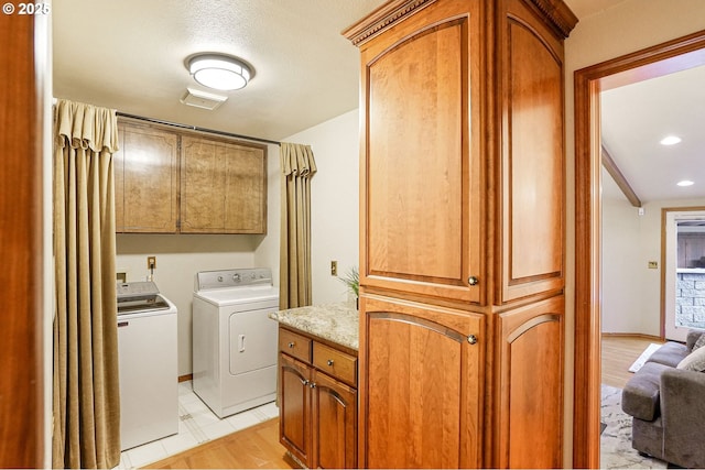 laundry room featuring a textured ceiling, cabinets, and independent washer and dryer