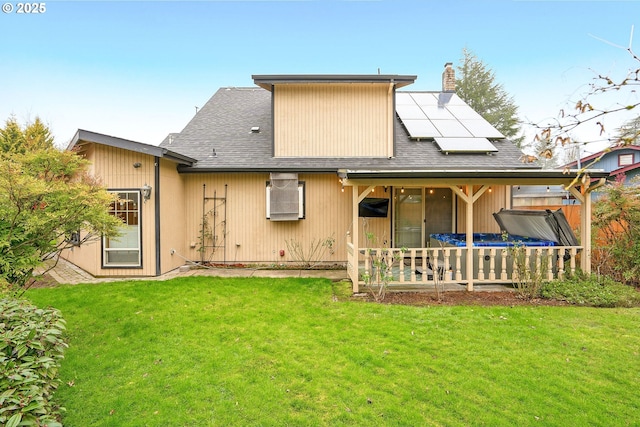 rear view of house with a yard and solar panels