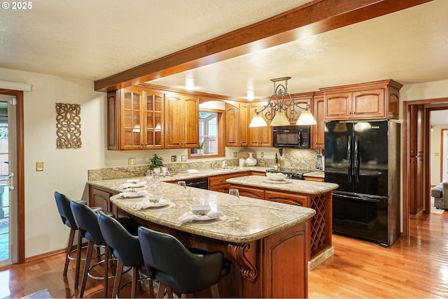 kitchen with black appliances, decorative light fixtures, light hardwood / wood-style floors, and a kitchen island