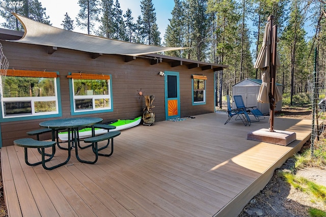 wooden deck with a storage unit, an outdoor structure, and outdoor dining space