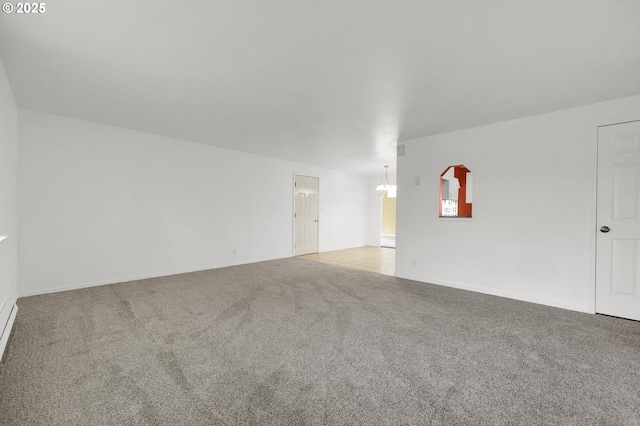 carpeted spare room featuring a chandelier