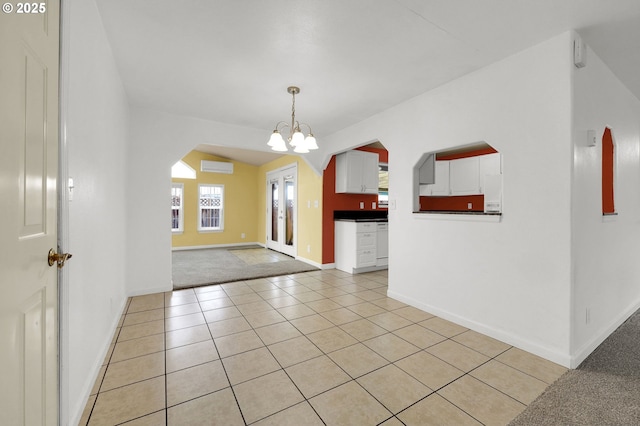 interior space with lofted ceiling, a wall unit AC, light tile patterned floors, and a chandelier