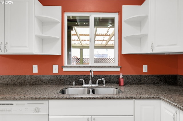 kitchen featuring white cabinets, dishwasher, dark stone countertops, and sink