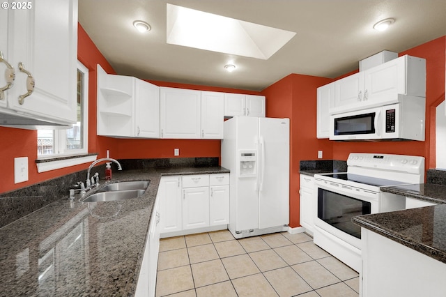 kitchen featuring sink, white cabinetry, white appliances, a skylight, and dark stone counters