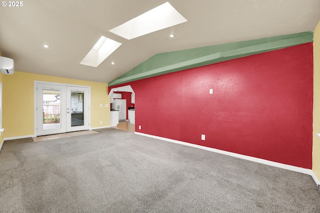 carpeted empty room featuring a wall unit AC, french doors, and lofted ceiling with skylight