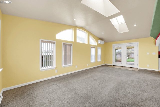 unfurnished room featuring a wall mounted AC, french doors, lofted ceiling with skylight, and carpet flooring