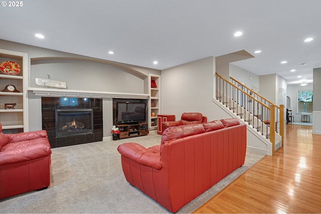 10886 SW Bretton Ct, Portland, OR 97224 - living area with built in shelves, stairs, a tiled fireplace, wood finished floors, and recessed lighting