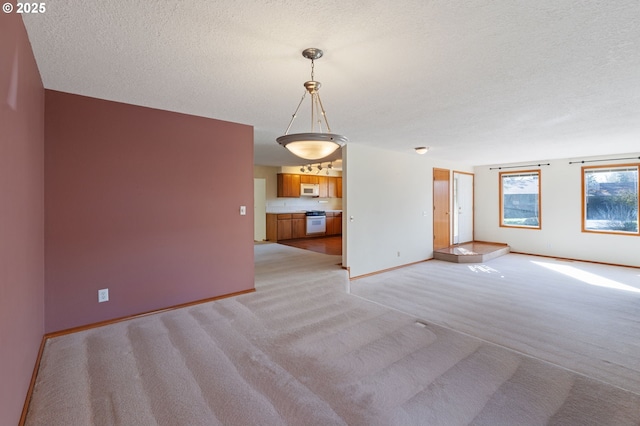 spare room featuring baseboards, light carpet, and a textured ceiling