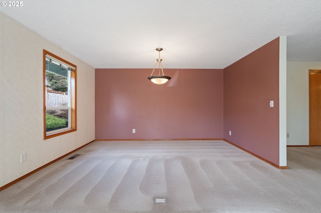 unfurnished room featuring visible vents, light colored carpet, a textured ceiling, and baseboards