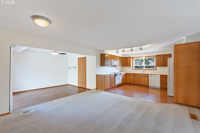 kitchen with visible vents, white appliances, open floor plan, and light countertops